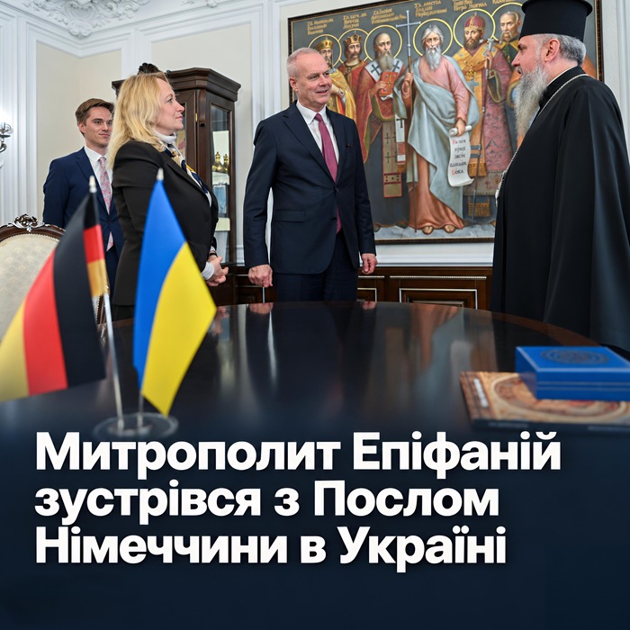 Митрополит Епіфаній у чорному клобуку вітає Посла Німеччини Бориса Руґе та співробітників Посольства; на столі прапорці Німеччини й України, позаду картина зі святими; напис «Митрополит Епіфаній зустрівся з Послом Німеччини в Україні»